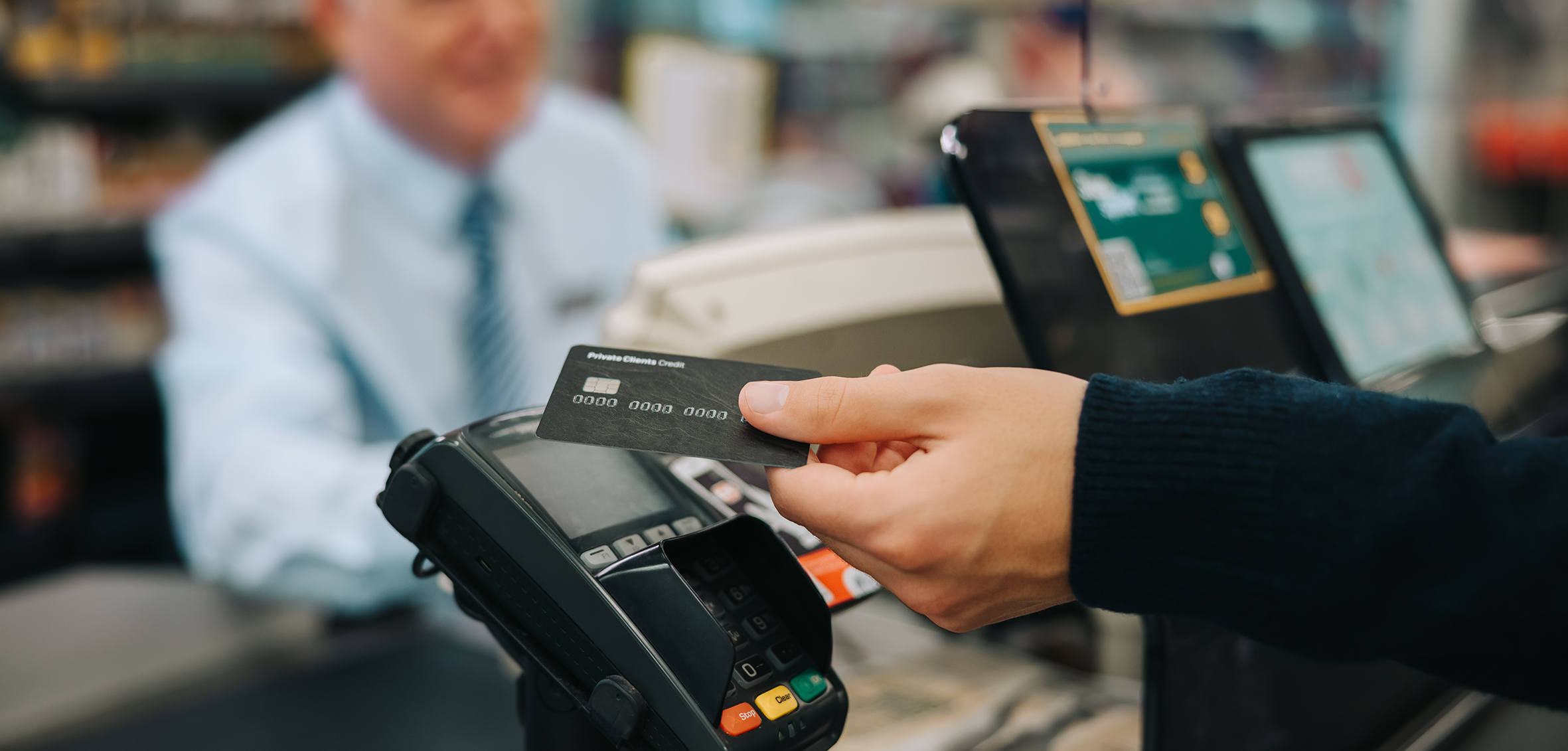 Close-up of a unrecognisable person using credit card to pay at grocery store.