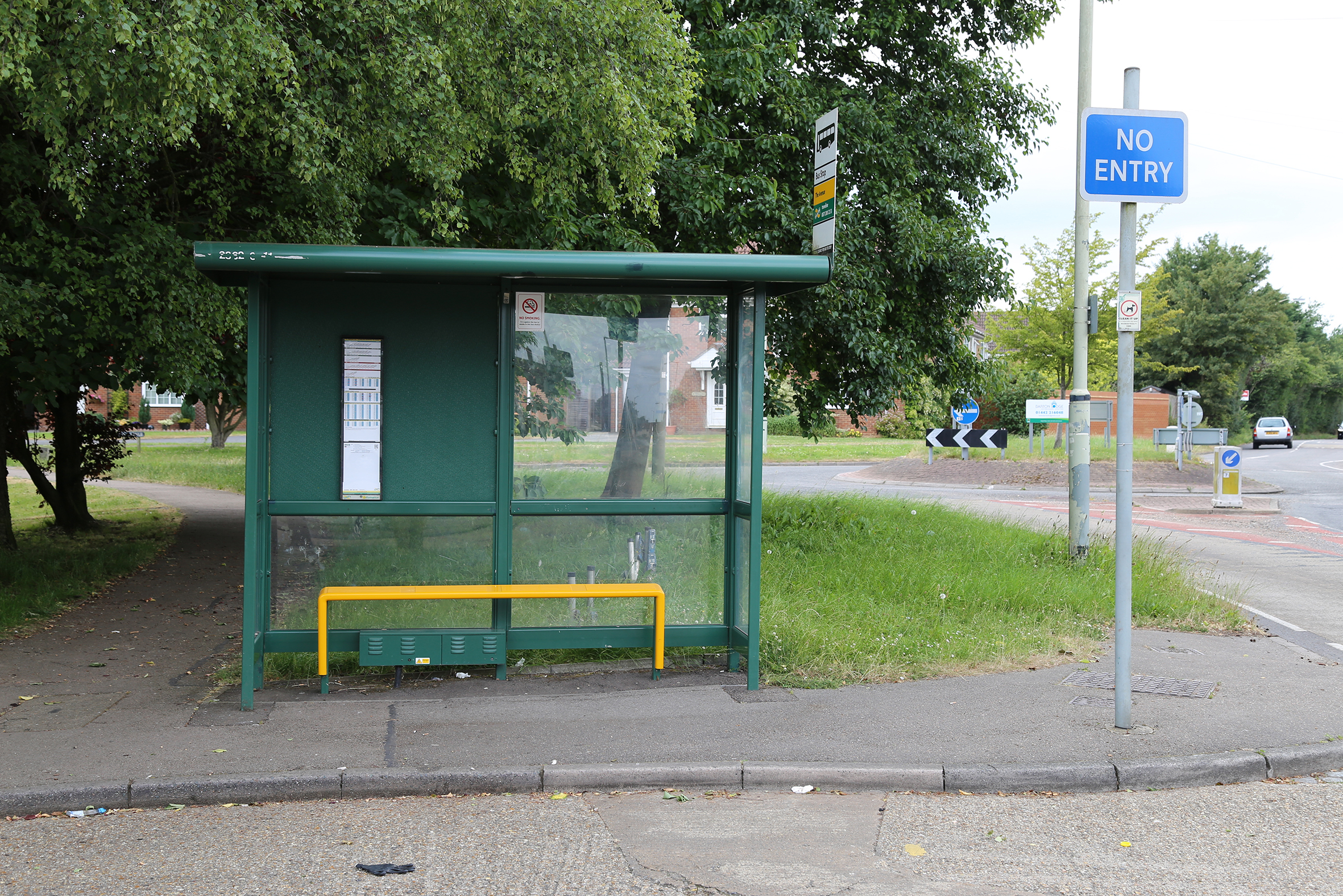 A green bus stop on the corner of a road