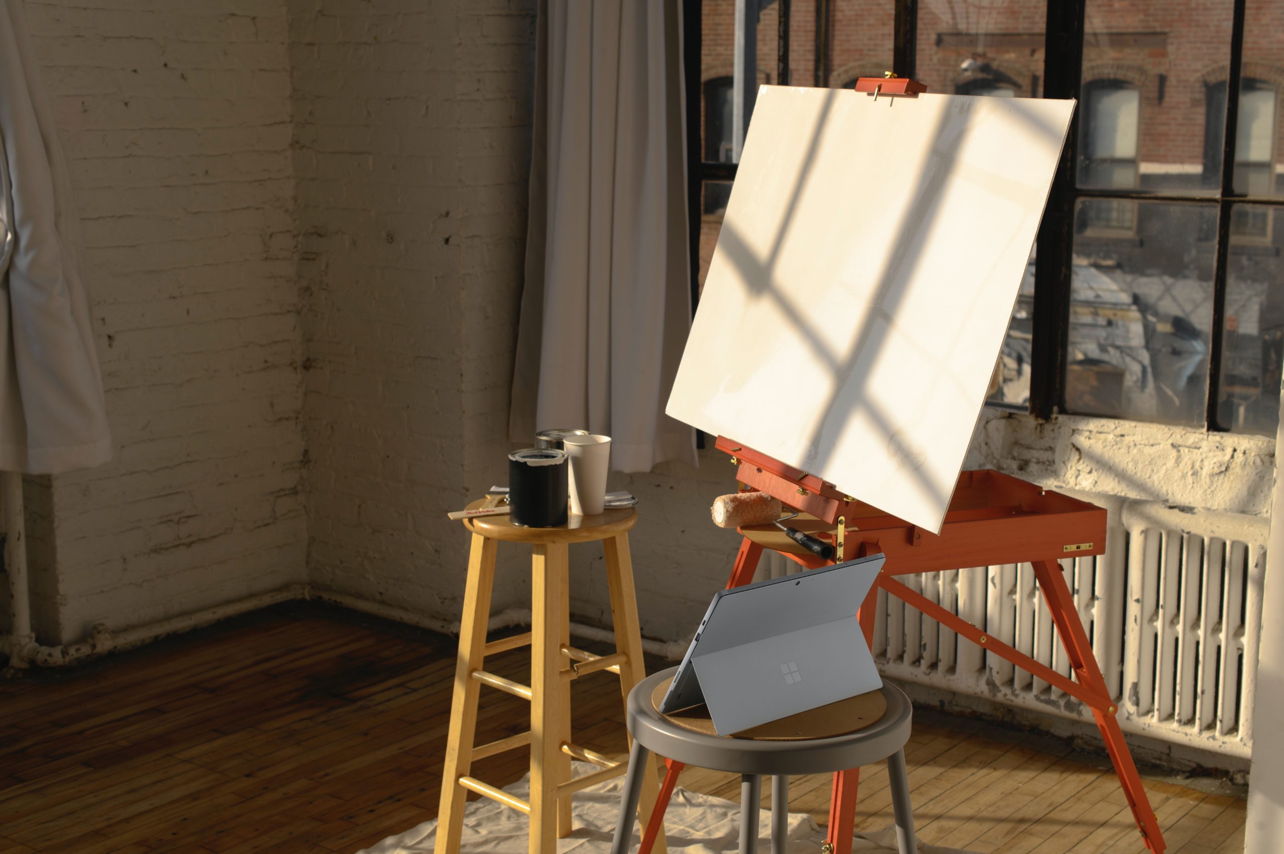 A laptop on a chair and a blank piece of paper on an easel